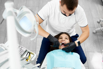 Attractive brunette is having her teeth attended by a male dentist in a modern dental clinic.