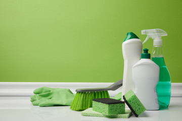 brush and domestic supplies for spring cleaning on green