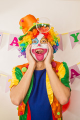 A clown boy in a bright suit at the baby's birthday party. The explosion of emotions and the fun of the circus. The sea of soap bubbles