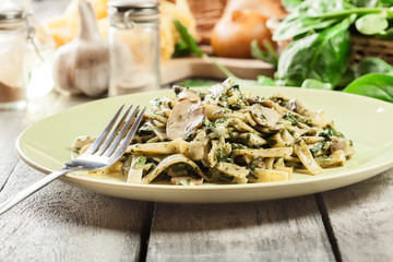 Tagliatelle pasta with spinach and mushrooms on a plate.
