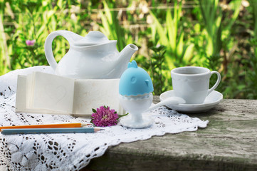 Breakfast with cup of coffee. Egg on white a lace tablecloth with green grass background. Note - good morning.
