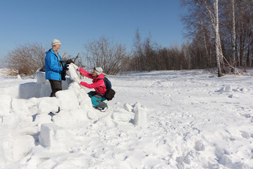 Man and woman building an igloo on a snow glade in the winter