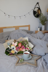 Bouquet of flowers and a cup of tea on the bed