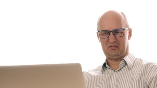 Businessman in glasses working at laptop saw disgusting image. Man made an expression of disgust while working in office behind laptop. Saw man is disgusting. Expressions of disgust