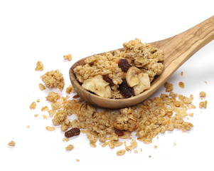 Crunchy granola, muesli pile with banana, pineapple slices, peanuts and raisins in wooden spoon isolated on white background