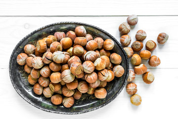Hazelnuts on an old iron plate on a white wooden background.Top view. Flat lay.The concept of healthy food