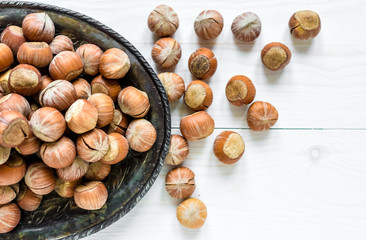Hazelnuts on an old iron plate on a white wooden background.Top view. Flat lay.The concept of healthy food