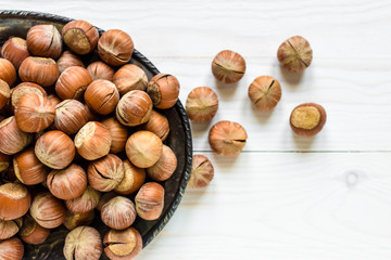 Hazelnuts on an old iron plate on a white wooden background.Top view. Flat lay.The concept of healthy food