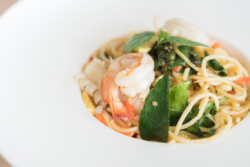 Spaghetti spicy seafood with basil on plate.