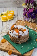 Easter cake (bread) decorated with candies, dried apricots and sunflower seeds on wooden background. Holidays concept