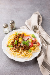 Rustic plate of tasty spaghetti Bolognaise topped with minced beef, grated parmesan cheese, cherry tomatoes and fresh basil. Copy space.