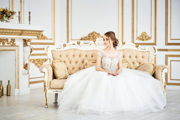 Young gorgeous bride is sitting in antique couch