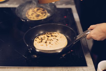 Frying traditional imeruli on frying pan in the kitchen.