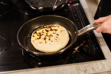Frying traditional imeruli on frying pan in the kitchen.