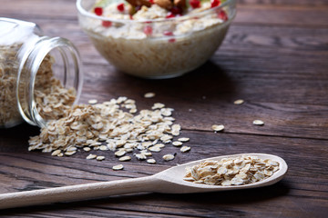 Composition with bowl of oatmeal porrige and dry oatmeal in glassware on vintage wooden table, selective focus