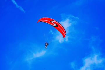 Paragliding over the ocean on the island of Bali. The blue sky shimmers with the blue ocean. The parasutists fly high above the precipice like birds. Aerial view with copy space