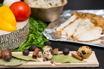 Close up of quail eggs on a wooden board on wooden board, baked chicken breast on foil near plate of rice