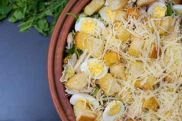 High angle view of large clay dish with appetizing caesar salad on a gray background