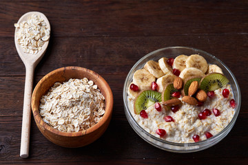 Diet breakfast oatmeal with fruits, bowl and spoon with oat flakes, selective focus, close-up