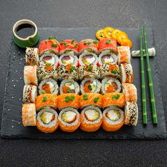 Sushi rolls, maki, nigiri Set served for two on black stone slate on dark background copy space