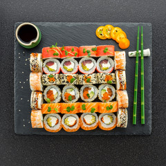 Sushi rolls, maki, nigiri Set served for two on black stone slate on dark background copy space