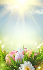 Easter holiday scene background. Traditional painted colorful eggs in spring grass over blue sky....