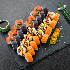 Sushi rolls, maki, nigiri Set served for two on black stone slate on dark background copy space