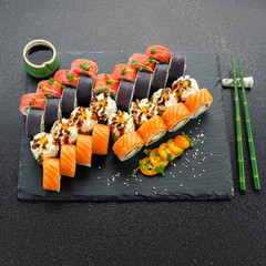 Sushi rolls, maki, nigiri Set served for two on black stone slate on dark background copy space