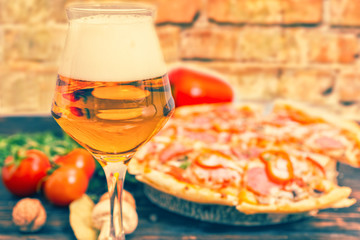 Glass of beer and pizza with salami on background