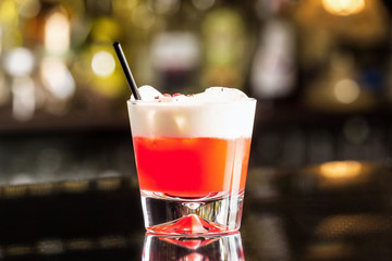 Closeup glass of special sex on beach cocktail decorated with cream at bar counter.