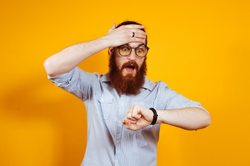 Bearded hipster man with eyeglasses in casual looking shocked at watch, You are late.