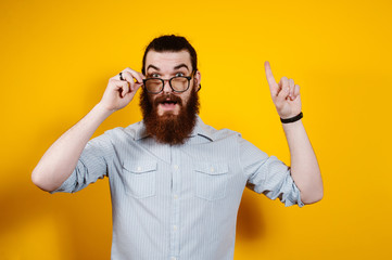 Portrait of a young business man having idea and pointing finger up isolated on yellow background