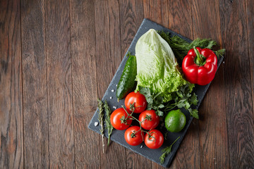 Vegetarian still life of assorted fresh vegetables and herbs on vintage wooden background, top view, selective focus.
