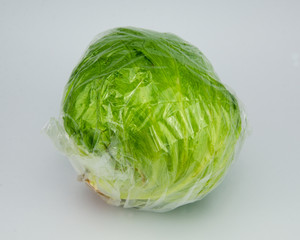 Fototapeta premium lechuga iceberg en envase de plástico con fondo blanco