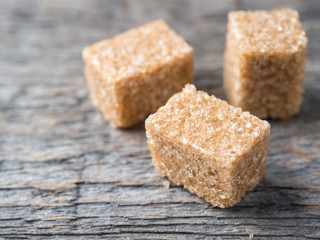 Brown cane sugar on wooden background.