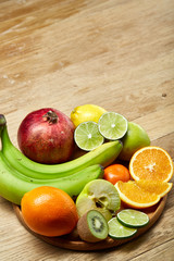 Ripe fresh fruits in a wooden plate on a light wooden background, selective focus, close-up, top view