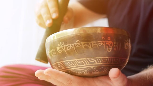 Man Playing on Traditional Tibetan Bronze Singing Bowl. Yoga Meditation Zen Practice with Calm Sounds for Good Energy and Health. 4K, Slowmotion.