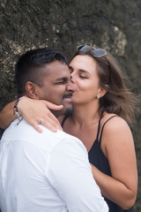 Outdoor portrait of romantic kissing young couple in sandy beach. Concept of honeymoon and true love