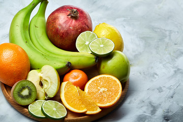 Ripe fresh fruits in a wooden plate on a light background, selective focus, close-up, top view