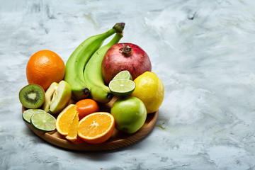 Ripe fresh fruits in a wooden plate on a light background, selective focus, close-up, top view