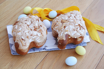 Two little Easter Colomba pasquale on wooden table. Italian sweet cake with sugar eggs 