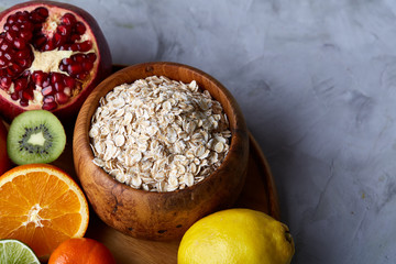 Bowl with oatmeal flakes served with fruits on wooden tray white background, flat lay, selective focus