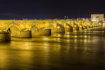 puente sobre río guadalquivir con mucha agua, larga exposición de noche