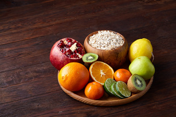 Bowl with oatmeal flakes served with fruits on wooden tray wooden background, flat lay, selective focus