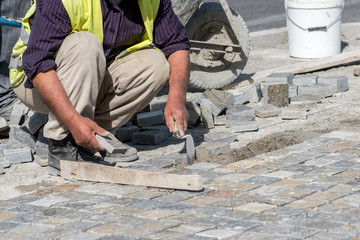 Construction worker installing stone blocks on the street.