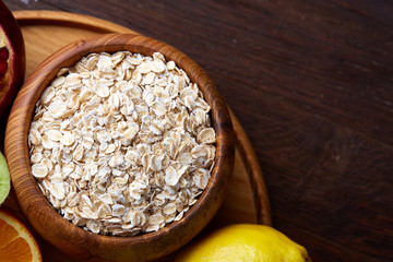 Bowl with oatmeal flakes served with fruits on wooden tray wooden background, flat lay, selective focus
