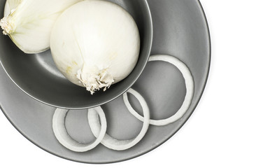 White onion top view set fresh pearls with three sliced rings on a grey plate isolated on white background.