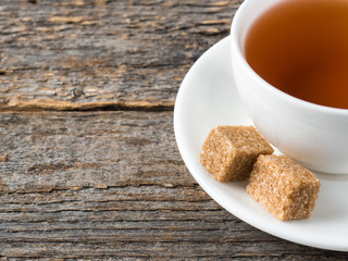 White tea Cup and saucer brown cane sugar on a rustic wooden background