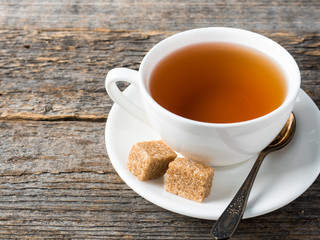 White tea Cup and saucer brown cane sugar on a rustic wooden background
