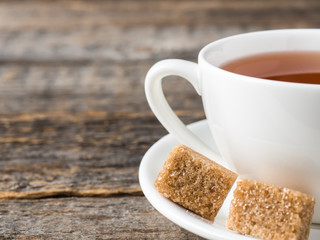 White tea Cup and saucer brown cane sugar on a rustic wooden background
